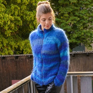 May include: A blue and grey striped fuzzy knit cardigan with a zip closure.