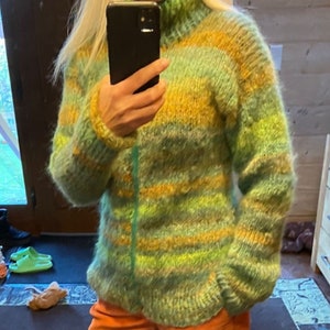 May include: A green, yellow and orange striped fuzzy sweater with a high neck.