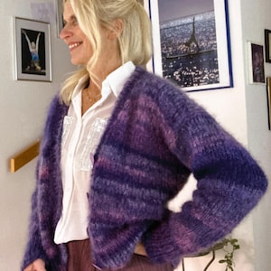 May include: A purple and blue striped fuzzy cardigan with a white button-down shirt underneath.