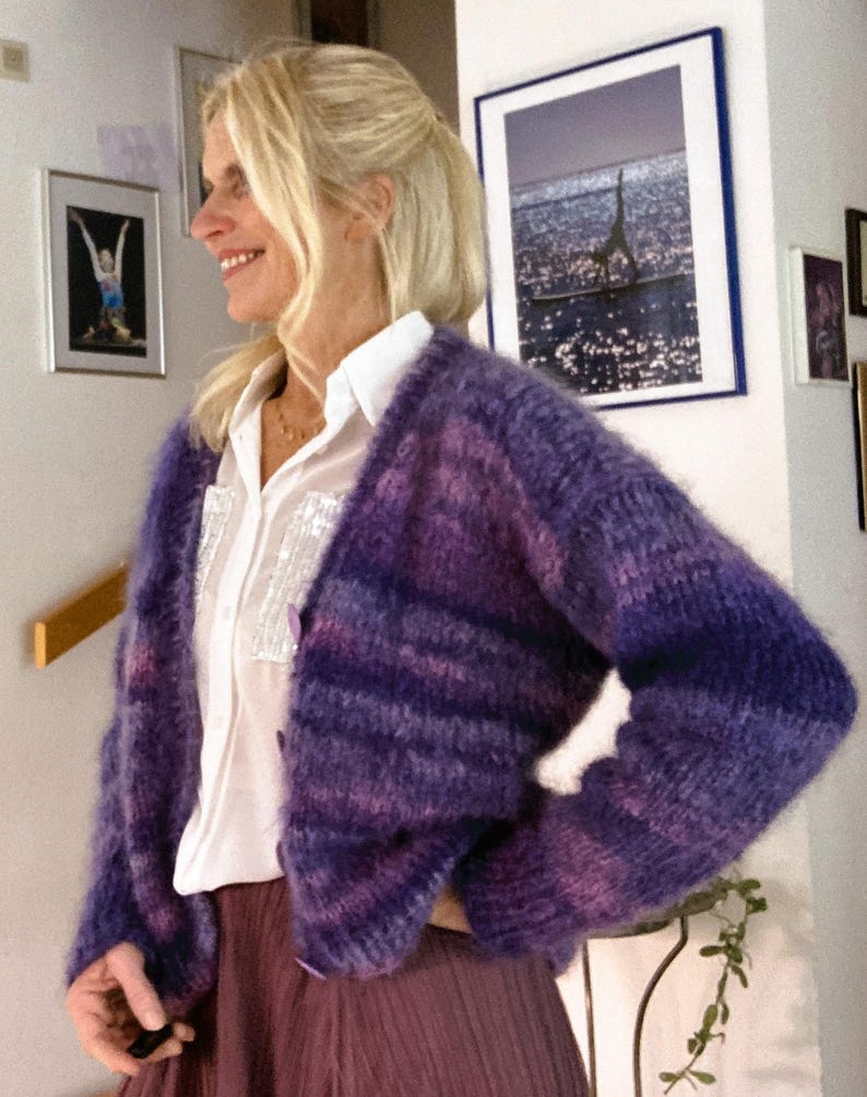 May include: A purple and blue striped fuzzy cardigan with a white button-down shirt underneath.