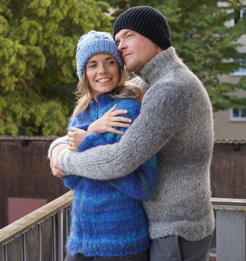 May include: A couple wearing knitted hats and jumpers, embracing each other while looking up at something in the distance.