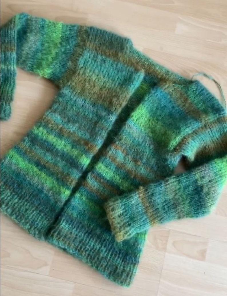 May include: A green, brown and yellow striped knitted cardigan with long sleeves.