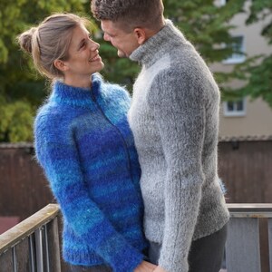 May include: A couple wearing fluffy sweaters, looking at each other and smiling. The woman is wearing a blue and turquoise sweater and the man is wearing a grey sweater.