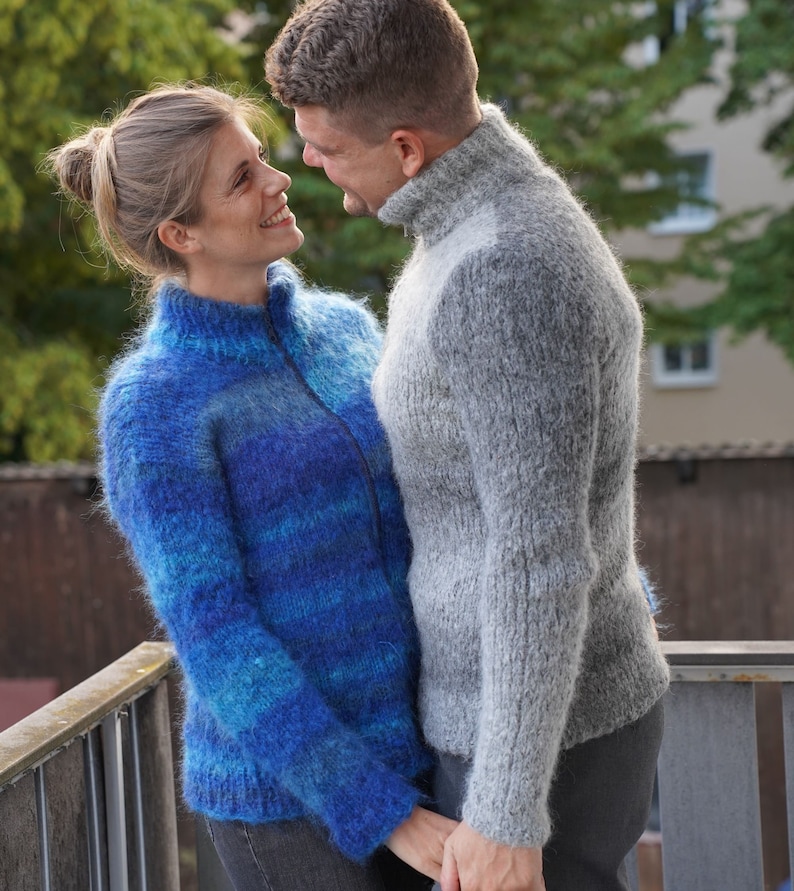 May include: A couple wearing fluffy sweaters, looking at each other and smiling. The woman is wearing a blue and turquoise sweater and the man is wearing a grey sweater.