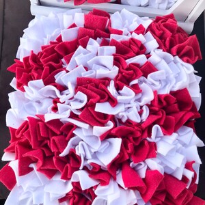May include: Red and white dog snuffle mat with a variety of fabric strips for dogs to sniff and play with.