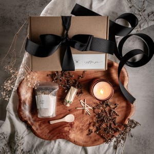 a wooden tray with various items arranged on it, including a candle, a bag of salt, a wooden spoon, and some dried flowers.
