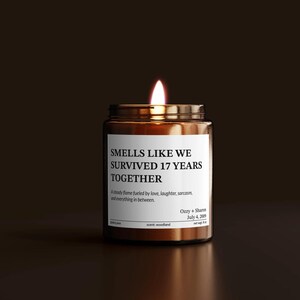 A brown glass jar with a lit candle inside, against a dark background.