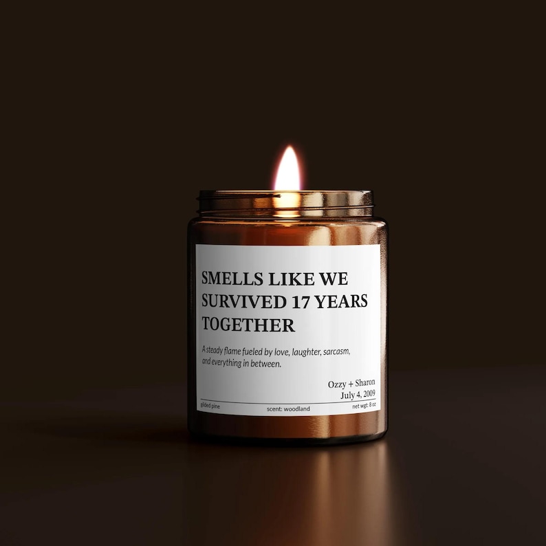 A brown glass jar with a lit candle inside, against a dark background.