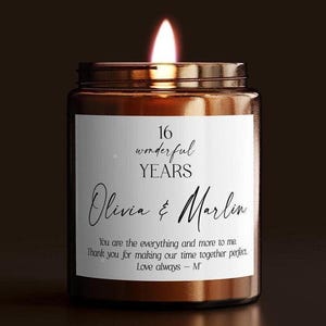 May include: A lit candle in a brown glass jar with a white label. The label reads: 16 wonderful YEARS, Olivia & Marlin, You are the everything and more to me. Thank you for making our time together perfect. Love always – M.