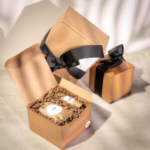 a set of brown cardboard boxes with black ribbons, some of which are open, revealing their contents. The boxes are placed on a surface with a white background.