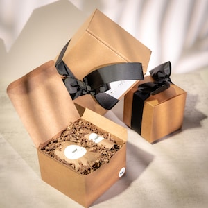 a set of brown cardboard boxes with black ribbons, some of which are open, revealing their contents. The boxes are placed on a surface with a white background.