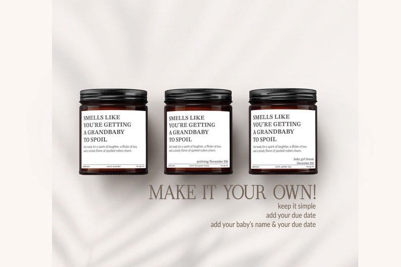 Three brown jars with black lids, each containing a different scent, are arranged in a row. The jars have white labels with black text that reads "Smells like you're getting a grandbaby to spoil". Below the jars, there is text that says "MAKE IT YOUR OWN! keep it simple add your baby's name & your due date".