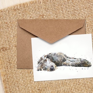 May include: A watercolour illustration of a grey dog lying on its side with its head resting on the ground. The dog has a white patch on its chest and a black nose.