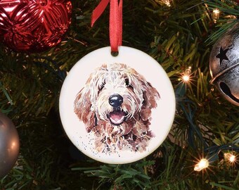 May include: Circular Christmas tree decoration with a watercolour image of a dog with brown and white fur. The ornament is suspended by a red ribbon, set against a festive Christmas tree with other decorations.