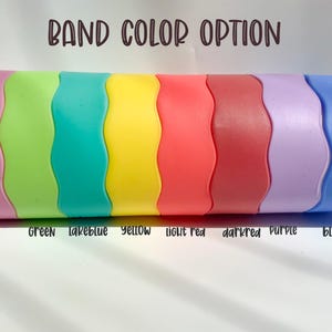May include: A row of eight silicone wristbands in different colors: pink, green, teal, yellow, light red, dark red, purple, and blue. The text "BAND COLOR OPTION" is at the top of the image. The colors are labeled below the bands.