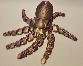 May include: A 3D-printed octopus figurine in shades of gold and purple. The octopus has a rounded head and eight articulated tentacles. The tentacles are made of linked segments, giving them flexibility. The figurine is designed to sit on a flat surface.
