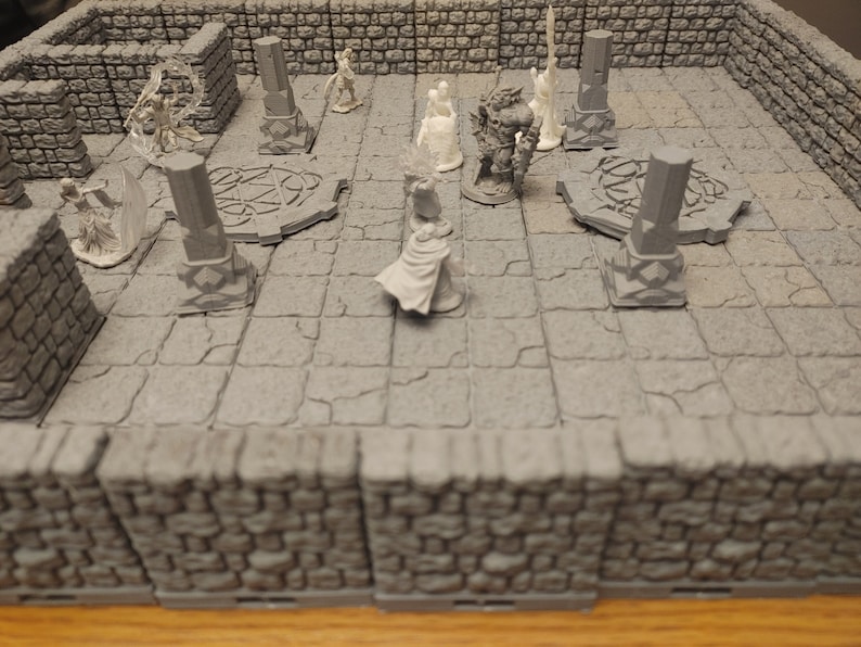 K&ouml;nnte beinhalten: Ein Miniatur-Tabletop-Spielset mit grauen Steinw&auml;nden und einem grauen Steinboden. Auf dem Boden befinden sich mehrere Miniaturfiguren, darunter ein Krieger, ein Zauberer und eine Kreatur. Die Figuren sind aus wei&szlig;em Kunststoff.