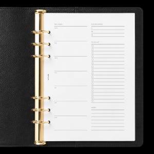 May include: A black leather planner with a gold six-ring metal binder mechanism. The white paper insert features a weekly layout with sections for top priorities, a to-do list with checkboxes, and notes. The text NOTAIRE is printed vertically.