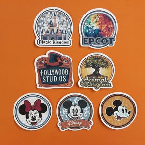 May include: Seven colourful round stickers with different Disney park logos. The stickers feature the Magic Kingdom castle, EPCOT, Hollywood Studios, Animal Kingdom, and three Mickey Mouse characters.