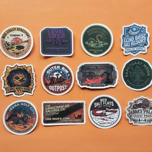 May include: A collection of twelve decorative stickers featuring various fictional locations and emblems. Designs include Mos Eisley Spaceport, Level 1313, Dagobah Planet Expeditions, Echo Base Ski Resort, The Spice Mines of Kessel, Outer Rim Outpost, Factory District, Sanctuary Moon, Jedha Holy City, The Sandcrawler Salvage Co., Red Salt Flats, and Jabba's Palace Guest Pass.