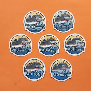 May include: Seven circular stickers featuring illustrations of P&O cruise ships. Each sticker shows a different ship name: Aurora, Arcadia, Ventura, Azura, Britannia, Iona, and Arvia. The ships are illustrated in a cartoon style, with blue water and a yellow background.