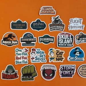 May include: A selection of colourful stickers showcasing theme park attractions and characters. Designs include "Jurassic Park," "Harry Potter," "Spider-Man," and Dr. Seuss characters. The stickers are displayed on an orange background.