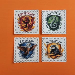 May include: Four square stickers featuring the crests of the Hogwarts houses: Gryffindor, Slytherin, Ravenclaw, and Hufflepuff. Each crest is set within a white, postage stamp-style border. The background is a solid orange.