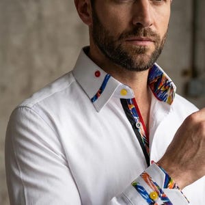May include: White dress shirt with a patterned collar and cuffs. The collar and cuffs have a vibrant design with red, blue, yellow, and black accents. The shirt has a button-down front with red, yellow, and black buttons.
