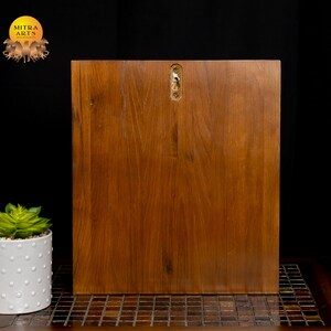 K&ouml;nnte beinhalten: Ein Wandregal aus Holz mit brauner Oberfl&auml;che. Das Regal hat ein schlichtes Design und ist bereit zum Aufh&auml;ngen an einer Wand.