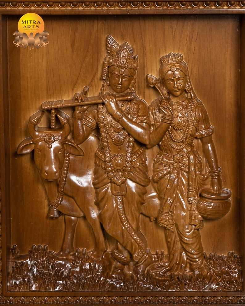 K&ouml;nnte beinhalten: Eine Holzschnitzerei von Krishna und Radha, wobei Krishna eine Fl&ouml;te spielt und Radha einen Topf h&auml;lt. Die Schnitzerei ist detailliert und kunstvoll, mit einer Kuh, die neben ihnen steht.
