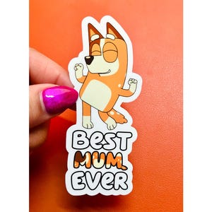 May include: White sticker with a cartoon dog in orange and white, with the text "Best Mum Ever" in black and orange.