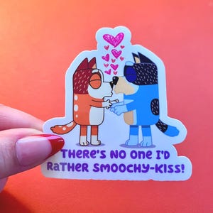 May include: A sticker featuring two cartoon dogs kissing, with pink hearts above them. One dog is orange and white, the other is blue. The sticker has the text "THERE'S NO ONE I'D RATHER SMOOCHY-KISS!"