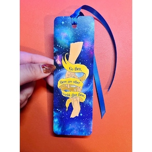 May include: A rectangular bookmark with a blue ribbon. The bookmark features a galaxy design with the text "Go then, there are other worlds than these." Two stylized hands are also depicted.