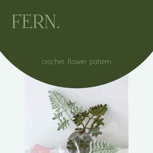 May include: A crochet flower pattern with the word "FERN" at the top. The image features a handmade crochet fern arrangement in a vase. The ferns are in shades of green and are displayed on a white background. The text "crochet flower pattern" is also visible.