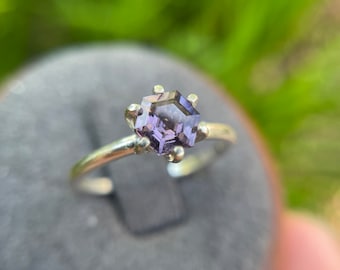 May include: A silver ring with a purple hexagonal gemstone set in a prong setting.