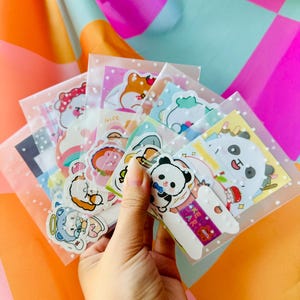 May include: A set of colorful stickers featuring cute cartoon animals, including a panda, a bear, and a rabbit. The stickers are packaged in clear plastic bags with white polka dots.
