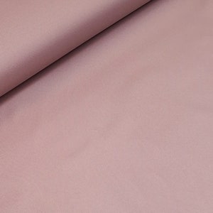 May include: A smooth, pale pink fabric with a subtle sheen. The fabric is folded in half, with one side lying flat and the other side folded over.