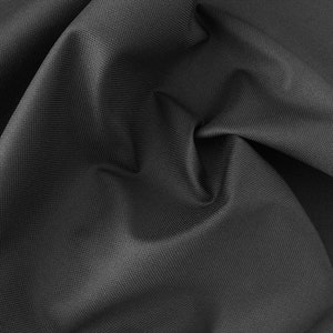 Puede incluir: Primer plano de una tela negra con tejido texturizado. La tela está doblada y drapeada, creando pliegues y arrugas suaves.