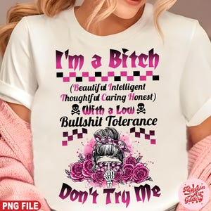 以下が含まれることがあります： ピンクと黒のグラフィックデザインの白いTシャツ。「I'm a Bitch」と「With a Low Bullshit Tolerance」というテキストが書かれています。デザインには、スカルグラフィック、ピンクのバラ、「Beautiful Intelligent Thoughtful Caring Honest」というフレーズが含まれています。