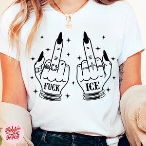 Peut inclure: T-shirt blanc avec un motif noir de deux mains faisant un doigt d'honneur. Le mot "FUCK" est imprim&eacute; sous une main et "ICE" sous l'autre. Les mains sont orn&eacute;es de bagues et de vernis &agrave; ongles noir.