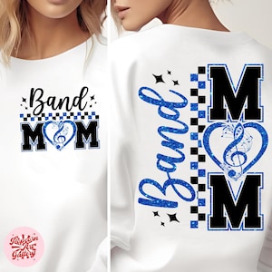 Może przedstawiać: Biała bluza z nadrukiem "Band Mom". Przód przedstawia napis "Band Mom" z sercem z nutą muzyczną. Tył ma napis "Band" w niebieskim brokacie i serce z nutą muzyczną z napisem "MOM".