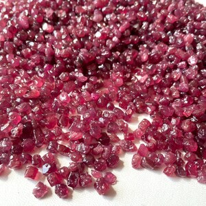 Puede incluir: Un montón grande de piedras preciosas de rubí rojo sueltas. Los rubíes son de varios tamaños y formas, algunos tienen una forma más puntiaguda.