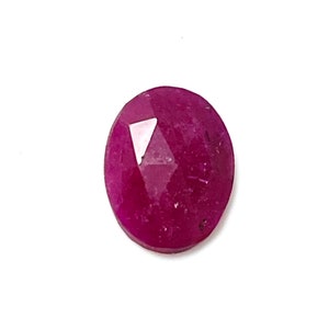May include: A deep red oval-shaped gemstone with a faceted cut.