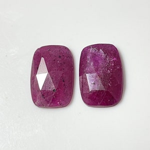 May include: Two pink faceted gemstone cabochons, each with a rectangular shape and a slightly irregular outline.