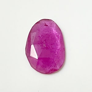 May include: A faceted pink gemstone with a smooth, oval shape.