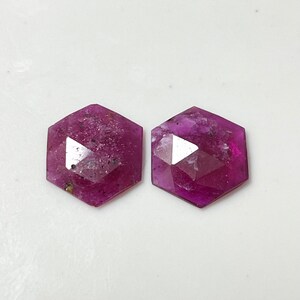 May include: Two pink faceted gemstone cabochons, each with a hexagonal shape.