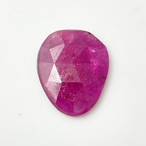 May include: A faceted pink ruby gemstone with a heart shape.