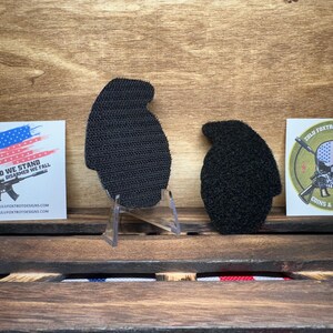 May include: Two black hook and loop patches, one shaped like a grenade and the other shaped like a skull with crossed rifles. The grenade patch has a white background and the skull patch has a green background with the text "Zulu Foxtrot Tactical Coins & Patches".