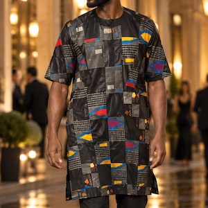 Peut inclure: Une tunique à manches courtes avec une base noire et un motif géométrique en patchwork aux accents jaunes, bleus et rouges. Le vêtement présente une encolure ronde, un ourlet droit avec des fentes latérales, porté avec un pantalon noir.