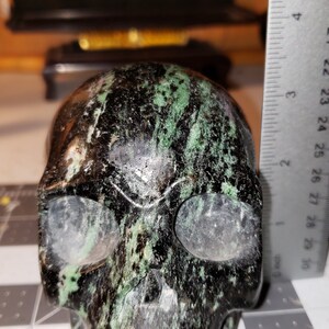 Puede incluir: Un cr&aacute;neo negro y verde hecho de piedra pulida. El cr&aacute;neo mide aproximadamente 5 cm de alto.